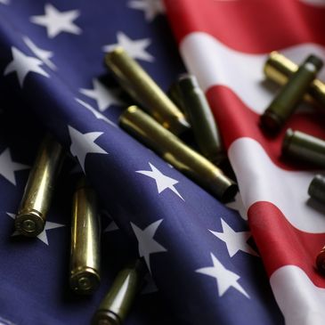 American flag with bullet casings scattered on it.