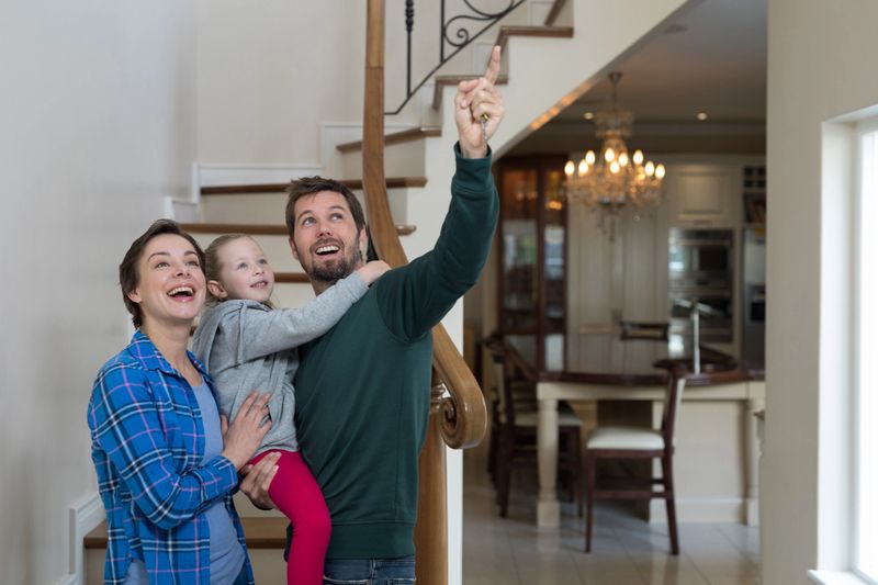 Parents and daughter standing on stairs at home