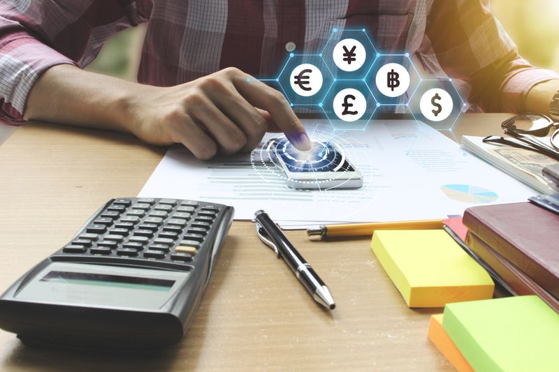 Businessman use smartphone with Currencies sign symbol of Fintech over the Network connection on the office desk, Investment Financial Technology Concept.