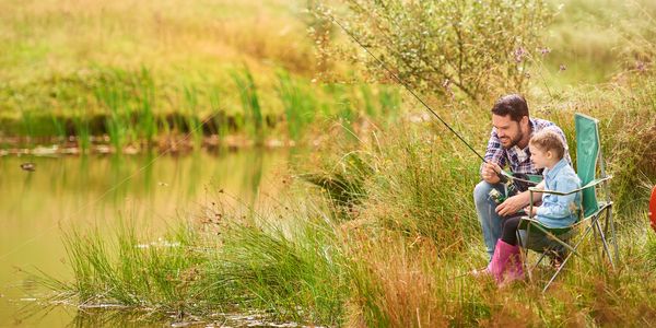 Father and child fishing by a lake.