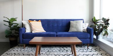 Modern living room with blue sofa, wooden coffee table, and plants.