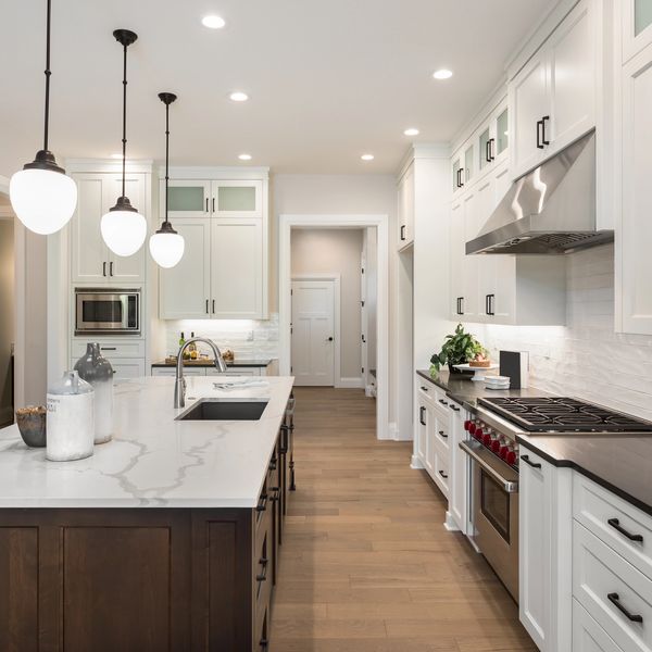 Modern kitchen with white cabinets, marble island, and pendant lights.