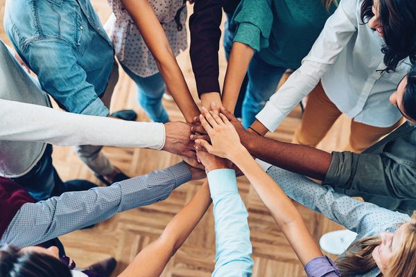 A group of people stacking hands on top of one another. 