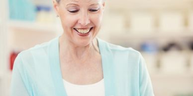 Smiling woman in a light blue cardigan looking down warmly.
