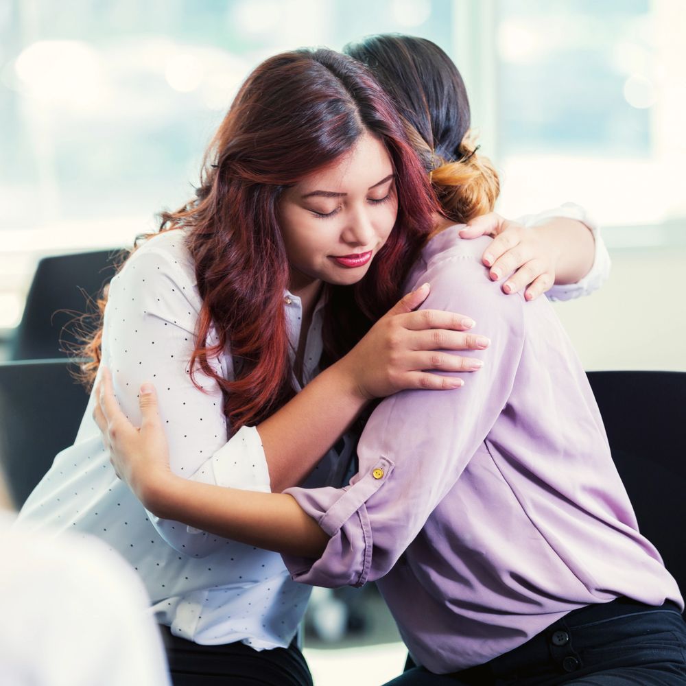 Two women sharing a warm, comforting hug indoors.