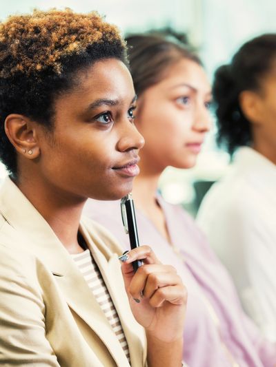 Focused woman holding a pen during a meeting or seminar.
