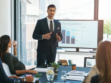 Businessman presenting data charts to colleagues in a meeting room.