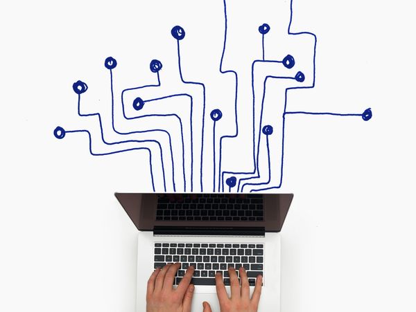 Hands typing on laptop with circuit-like lines emerging symbolizing digital connectivity.