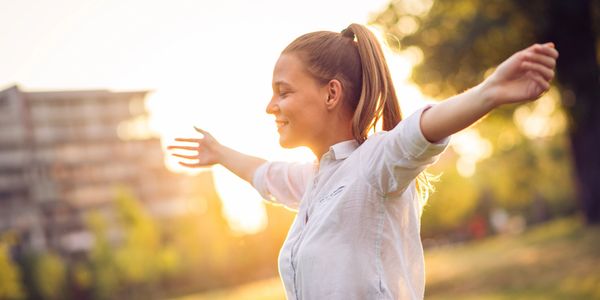 Woman with arms outstretched enjoying the sunlight outdoors.