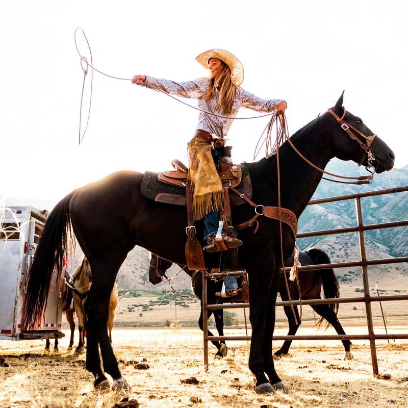 Little girl on horse with rope lasso.