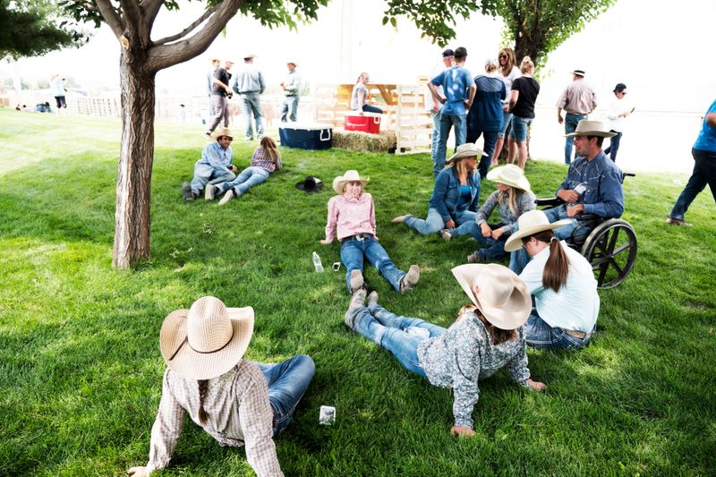 Group of cowboys and cowgirls relaxing in the grass after a rodeo event.
