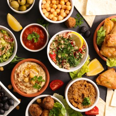 Mediterranean feast with dips, olives, falafel, and stuffed pastries.