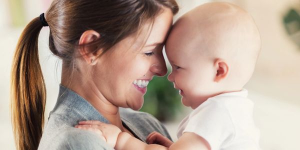 Mother and baby share a joyful, close moment together indoors.