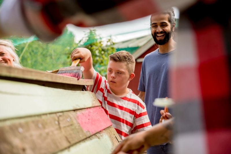 A child helps paint the hen hut at the farm.