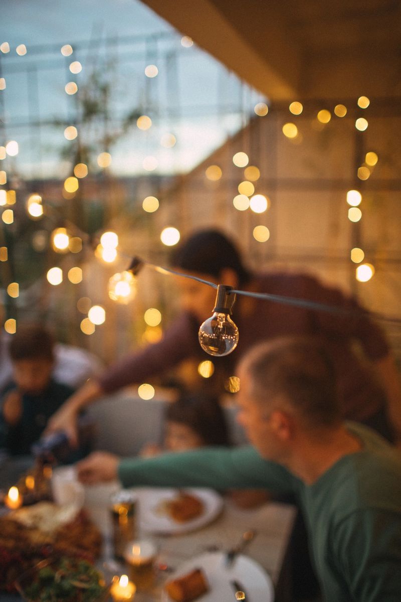 Photo of a multi-generation family having Thanksgiving dinner outdoors on their balcony; defocused