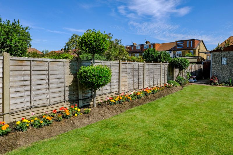 Backgarden tidy flower bed with fence and  newly mown grass.