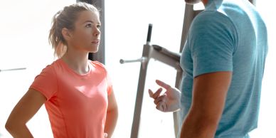A woman and a man having a conversation in a gym setting.