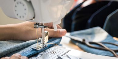 cropped view of hands guiding fabric on a sewing machine