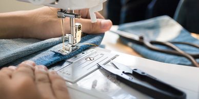 cropped view of hands guiding fabric on a sewing machine