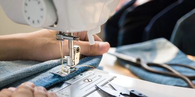 cropped view of hands guiding fabric on a sewing machine