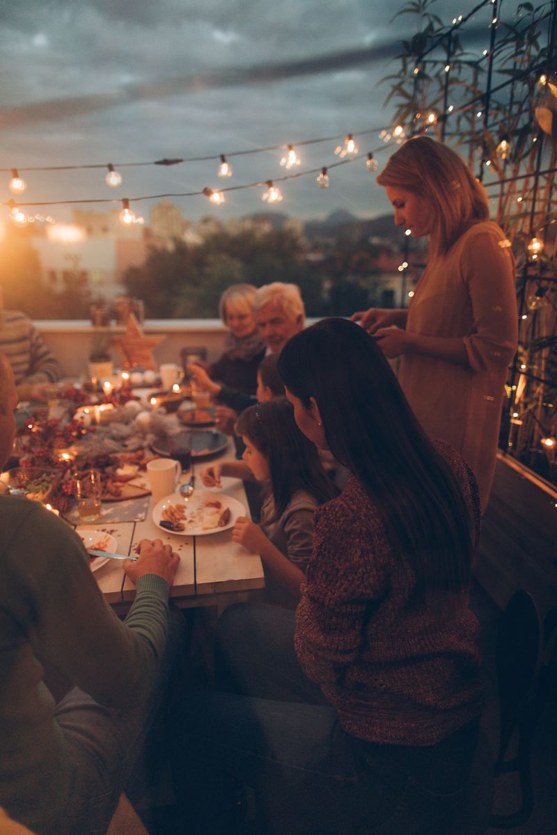 Photo of a multi-generation family having Thanksgiving dinner outdoors on their balcony