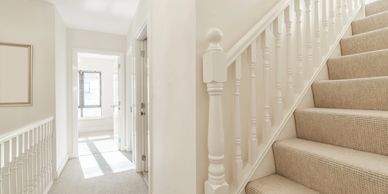Bright hallway with carpeted stairs and natural light.