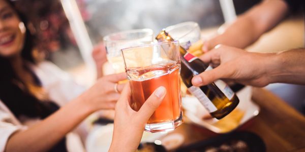 Friends clinking glasses and bottles in a cheerful toast.