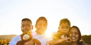 A happy family holding teddy bears at sunset.
