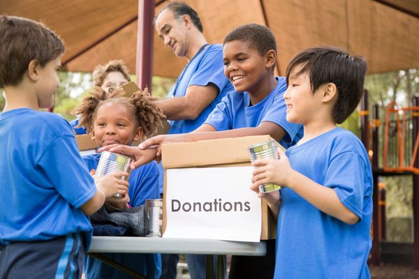 Four children receiving a donation box from an adult.