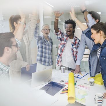Diverse team celebrating success with high-fives in a bright office.