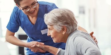 Nurse warmly assisting an elderly woman, showing care and support.