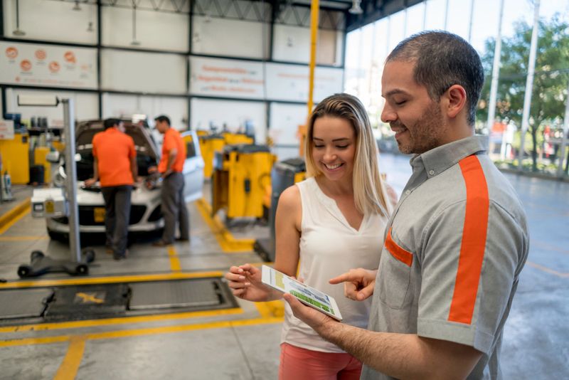 Mechanic talking to a female customer about her car at an auto repair shop - lifestyle concepts