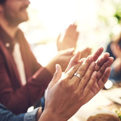 People clapping hands in appreciation during a gathering.