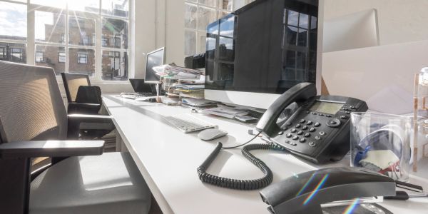 Bright office desk with phone and computer.