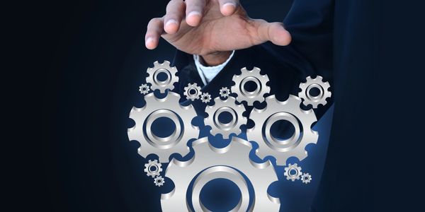 A hand controlling floating metallic gears symbolizing management or technology.