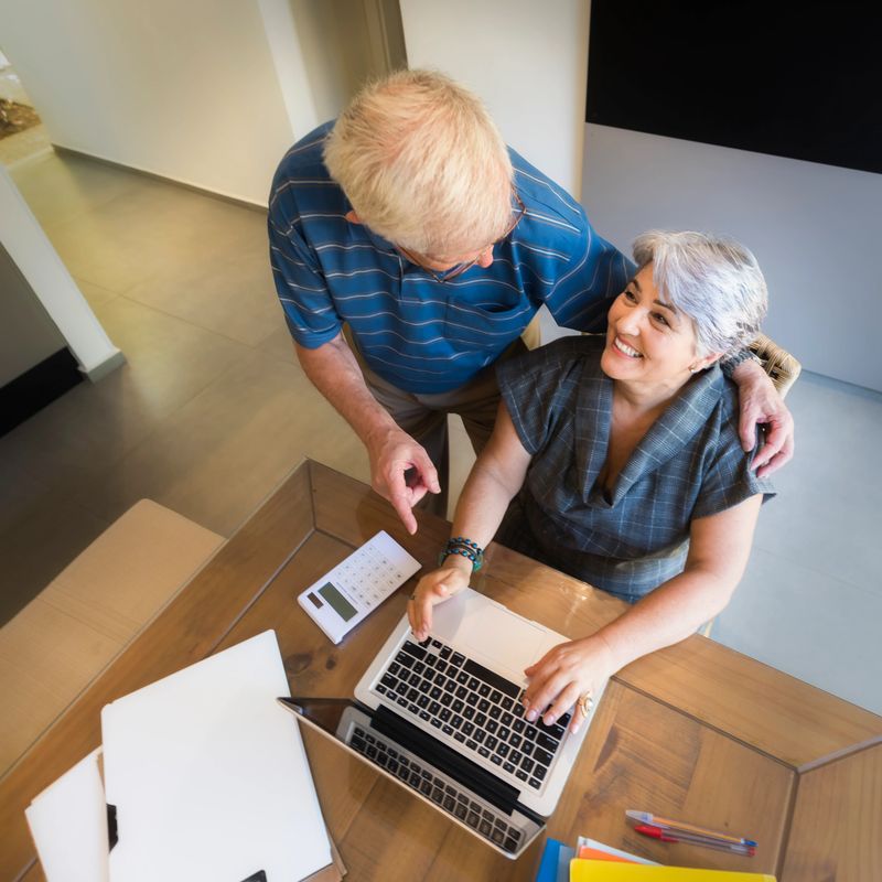 Senior man and senior woman with their laptops and smartphones having a good time making plans