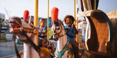 Children enjoying a carousel ride on white horses.