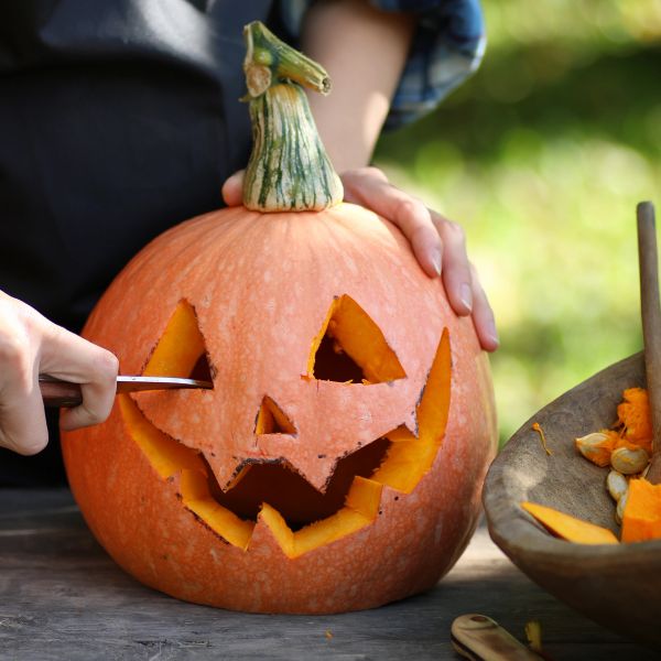 Person carving a jack-o'-lantern pumpkin.