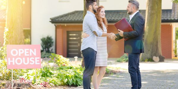 Couple shakes hands with real estate agent during an open house event.