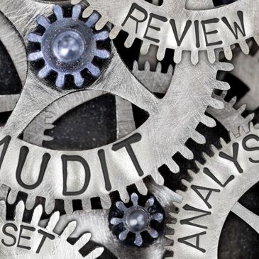 Close-up of metallic gears labeled audit, review, and analysis interlocking.