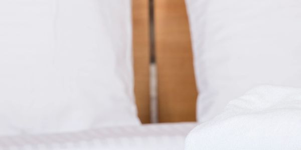 Close-up of neatly arranged white pillows and towel on a bed.