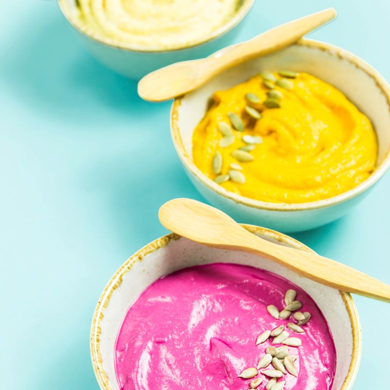 Snacks in the form of sauces from carrots, beets and hummus from chickpeas. in bowls on a contrasting blue background