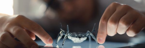 A person interacts with a small robotic spider on a tablet screen.