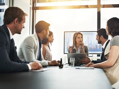 A businesswoman leading a meeting with colleagues around a conference table.