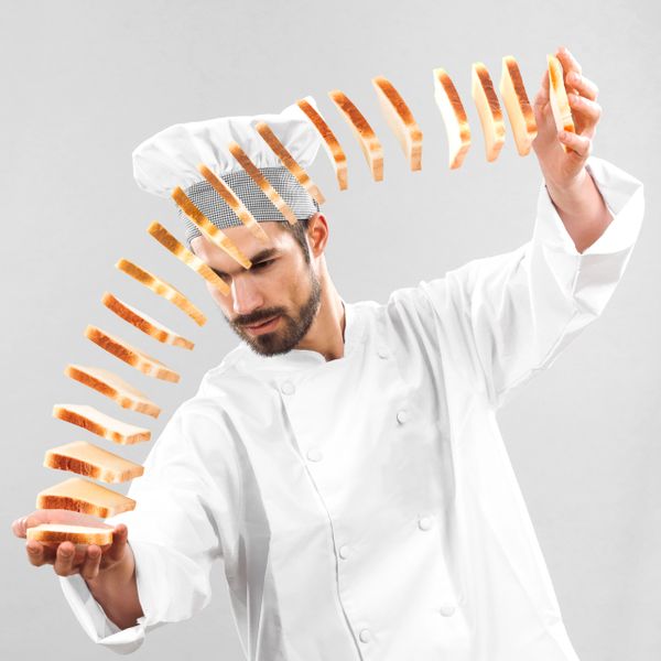 Chef tossing slices of bread in an artistic arc.