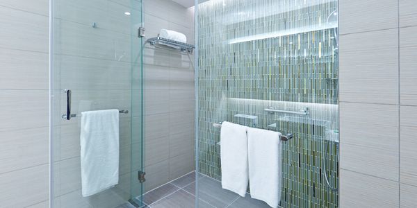 Wet room fully tiled with glass enclosure and concealed shower unit with mosaic tile design