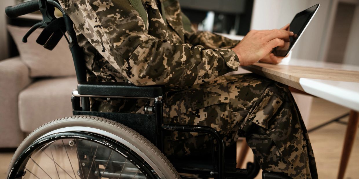 Photo of  the bottom half of a  veteran in wheelchair typing on computer 