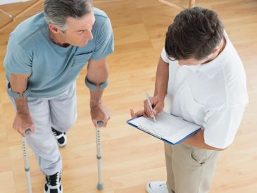 Man on crutches consulting healthcare professional.