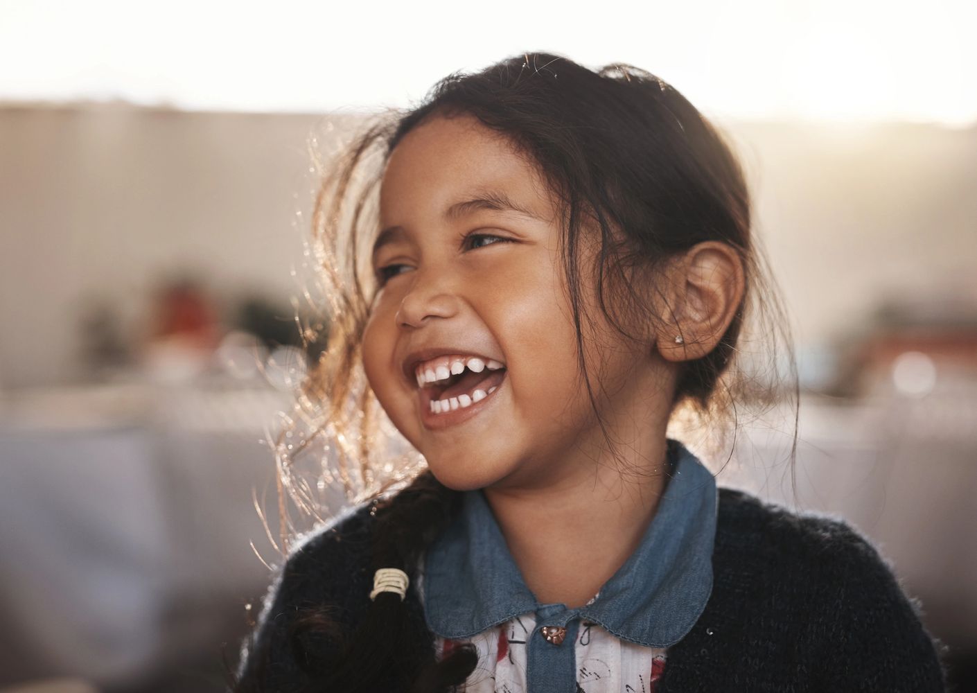 A young girl with a joyful smile and braided hair laughs warmly.