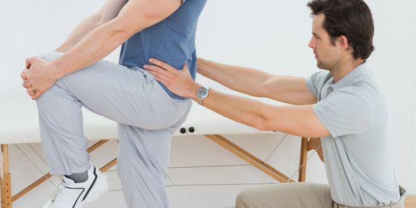A physiotherapist assists a patient with a leg stretch exercise.
